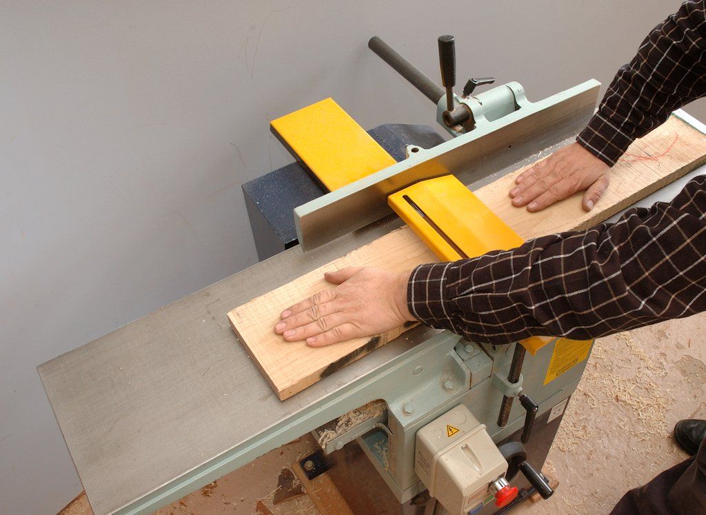 As John Bullar shows, timber is fed slowly from right to left, over the planer tables and cutter beneath the yellow guard