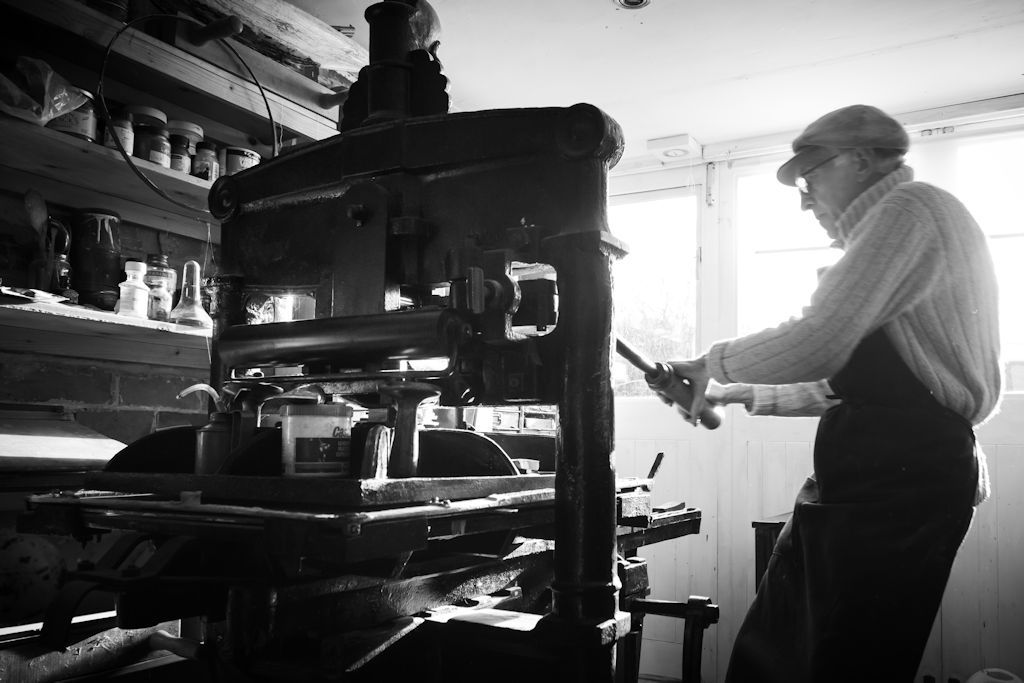 Bob Guy lowers the iron press’ platen on its wrist-thick thread with a characteristic sweep of the bar